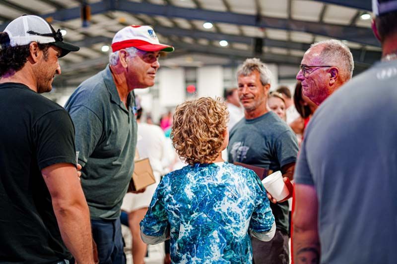 A group of people are standing around talking to each other in a room.
