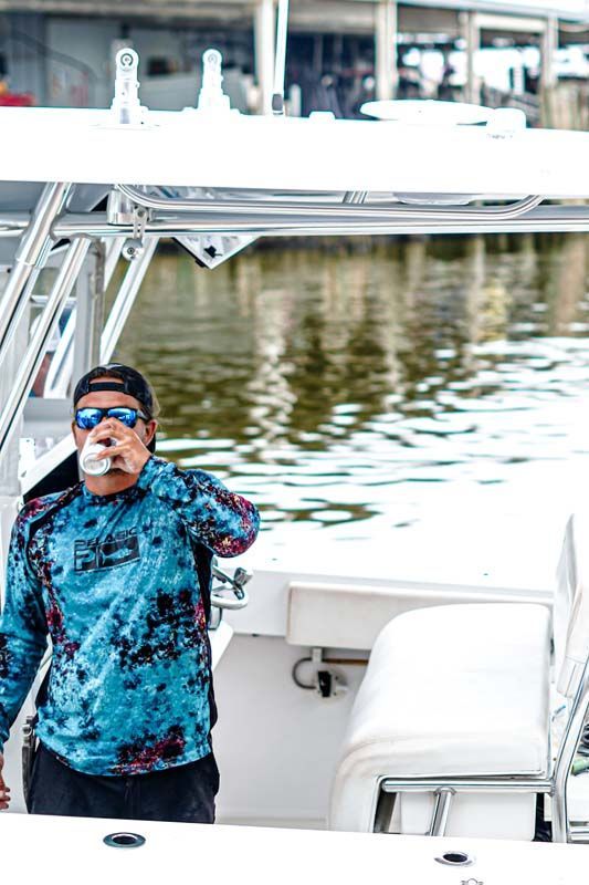 A man is standing on the back of a boat in the water.