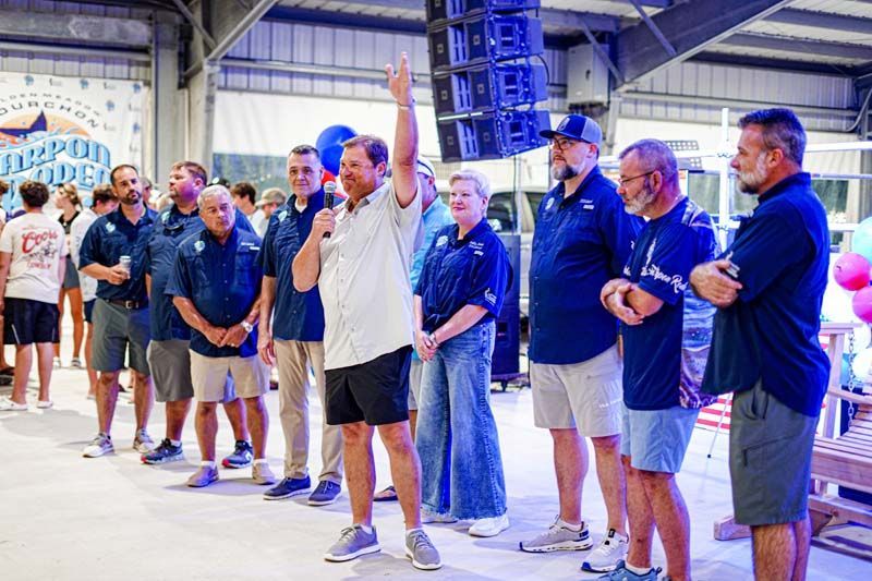 A man is standing in front of a group of people holding a microphone.