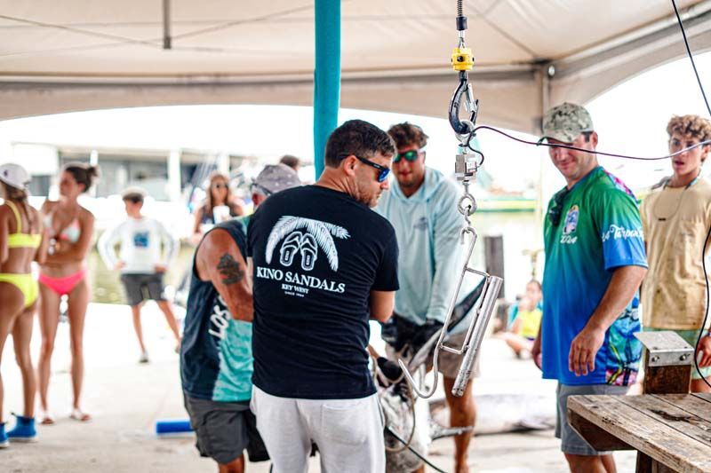A group of people are standing around a chair.