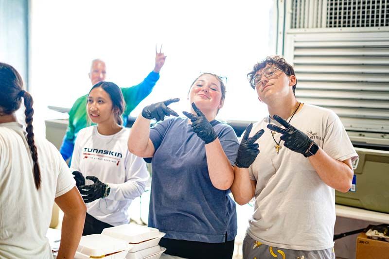 A group of people wearing gloves are standing next to each other in a room.