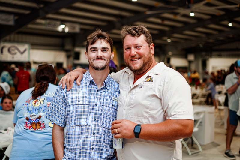 Two men are posing for a picture together in a crowded room.