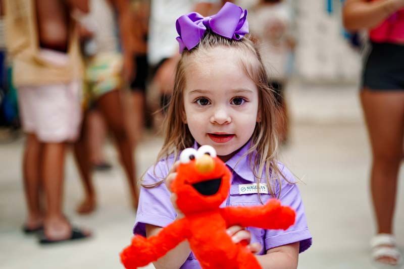A little girl is holding a stuffed animal in her hands.