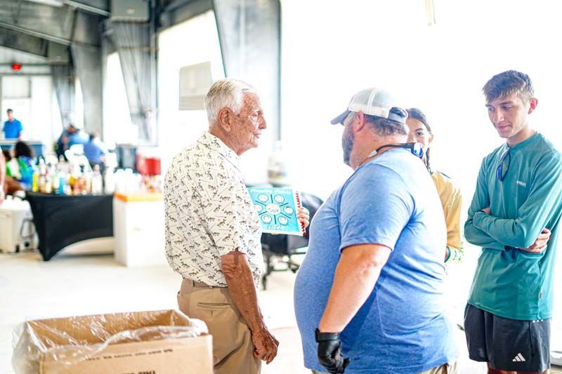 A group of people are standing around talking to each other in a room.