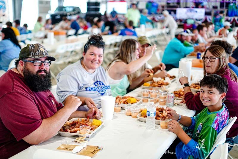 A group of people are sitting at a long table eating food.