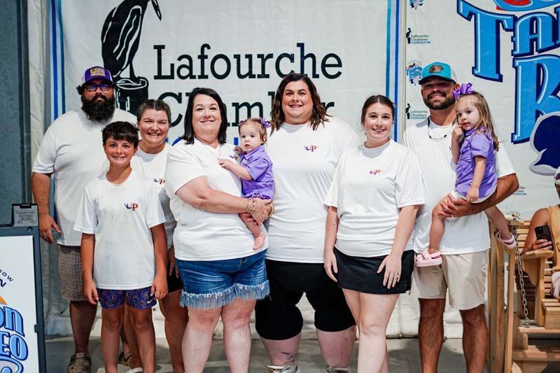 A large family is posing for a picture in front of a lafourche sign.