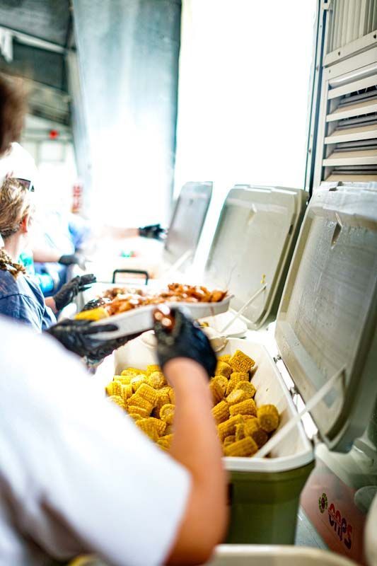 A person is standing in front of a cooler filled with food.