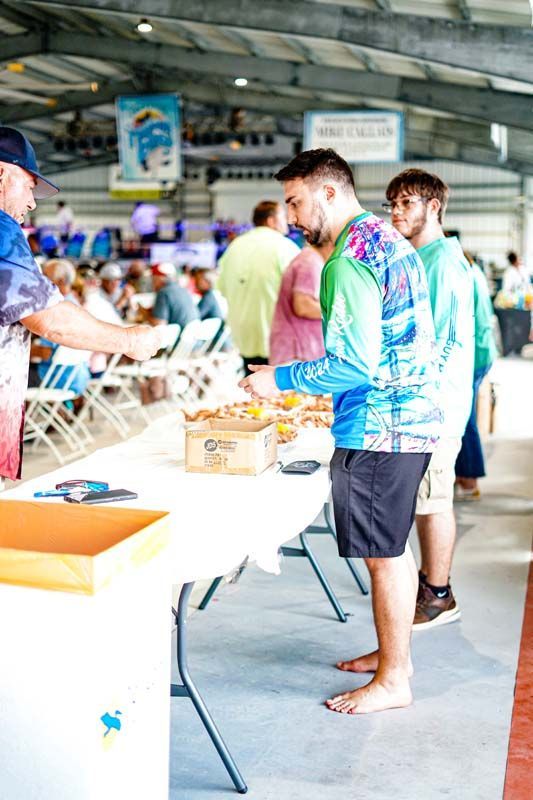 A group of men are standing around a table eating food.