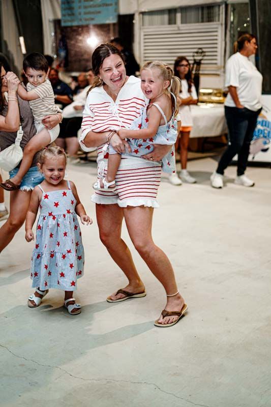 A woman is holding two children in her arms while dancing on a dance floor.