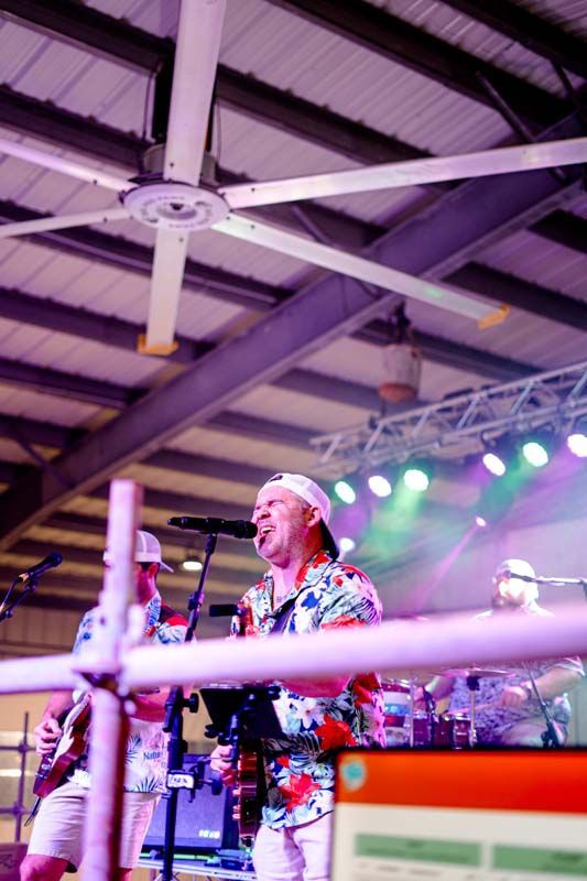 A man is singing into a microphone while playing a guitar on stage.