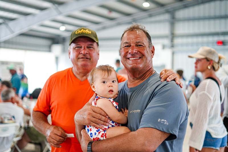 Two men are holding a baby in their arms and smiling for the camera.