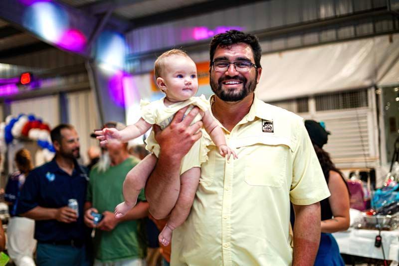 A man is holding a baby in his arms at a party.