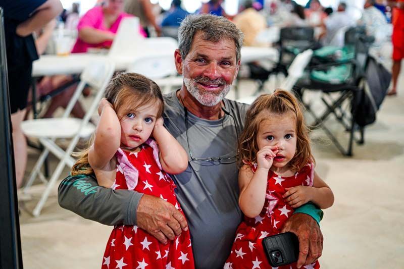 A man is holding two little girls in his arms.
