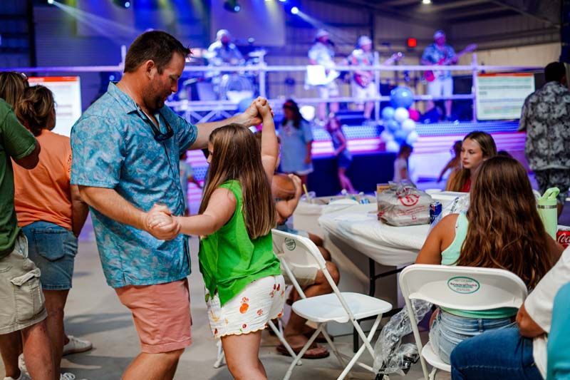 A man and a little girl are dancing at a party.