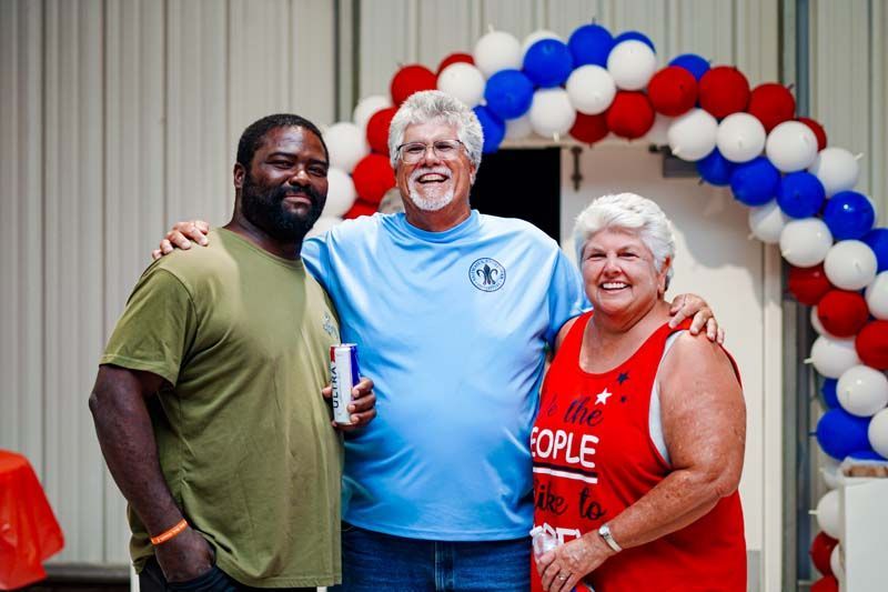 Three people are posing for a picture in front of balloons.