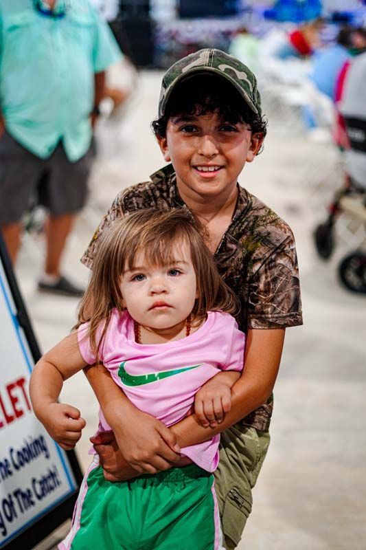 A boy is holding a little girl in his arms.