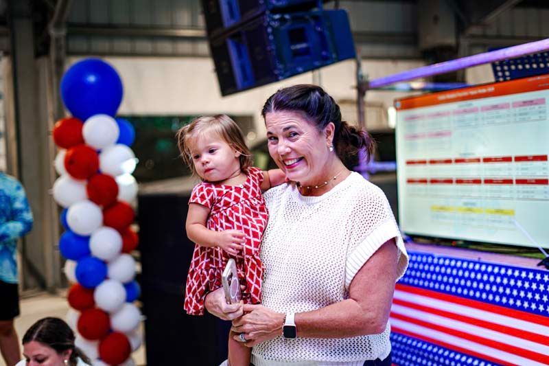 A woman is holding a little girl in her arms at a party.