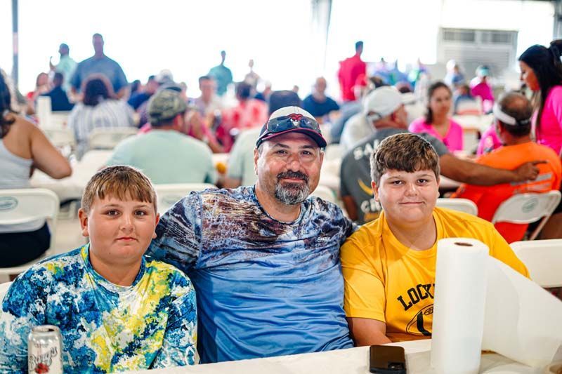 A man and two boys are posing for a picture while sitting at a table.