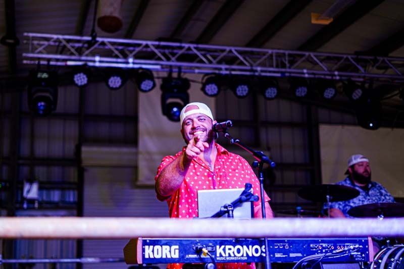 A man is standing in front of a korg keyboard on a stage.