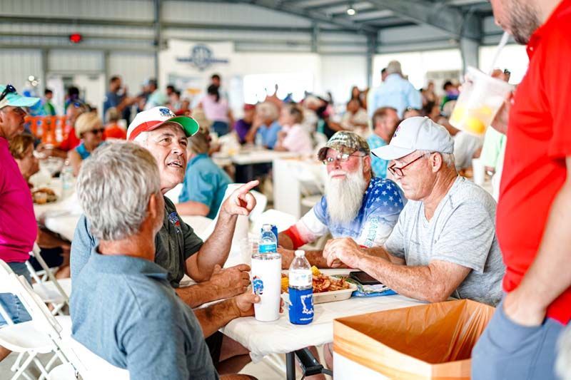 A group of men are sitting at tables eating food.