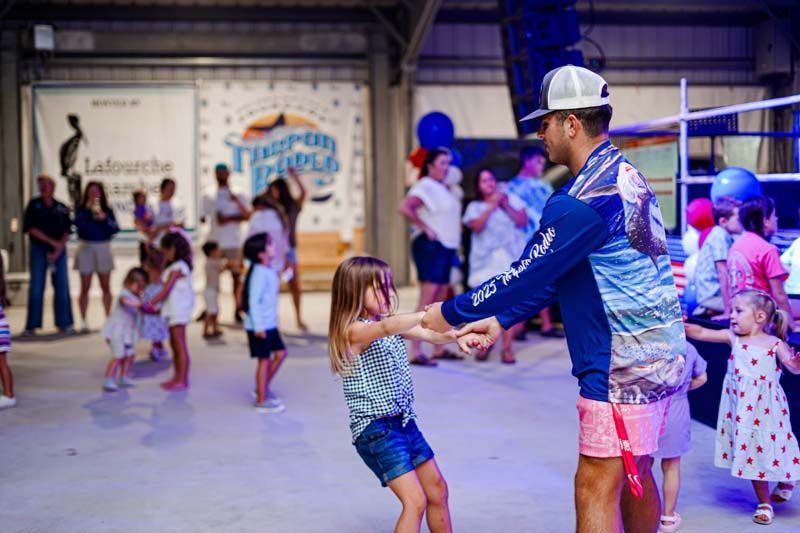 A man and a little girl are dancing together in a room.