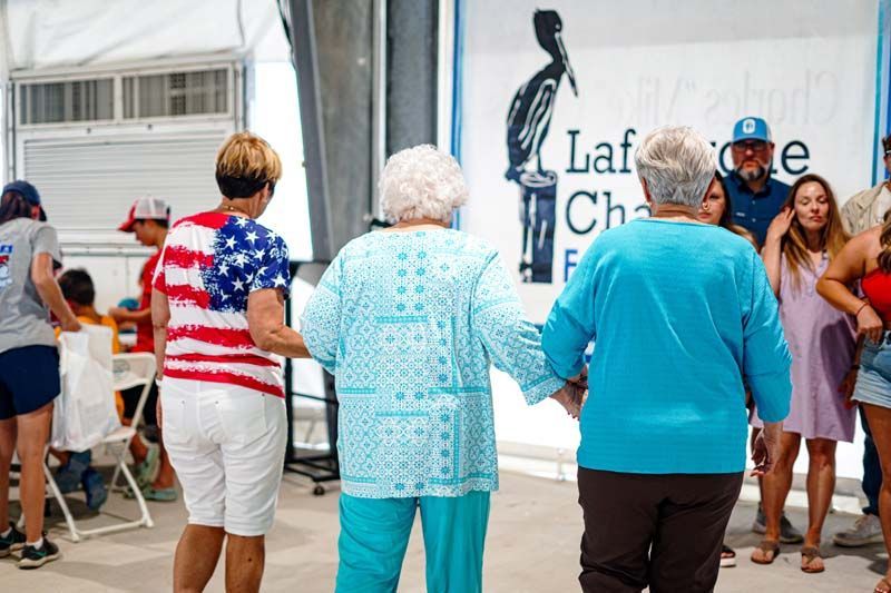 Two older women are holding hands while dancing in front of a crowd.