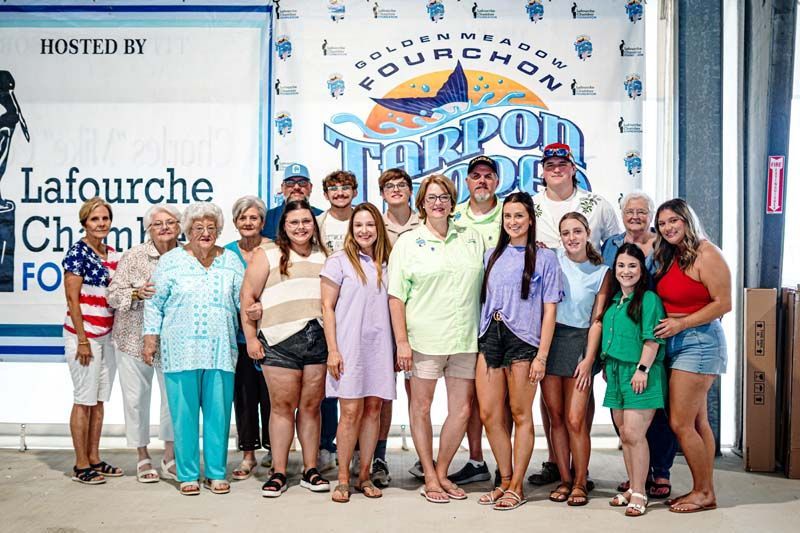A group of people are posing for a picture in front of a large sign.