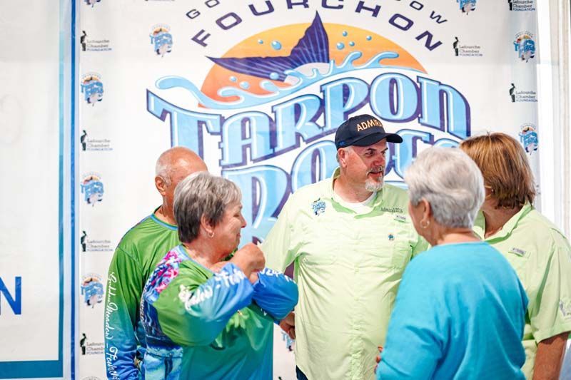 A group of people are standing in front of a tarpon doo sign.