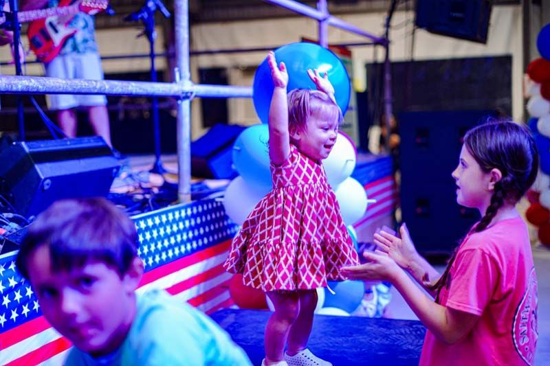 A little girl is standing on a stage with her arms in the air.