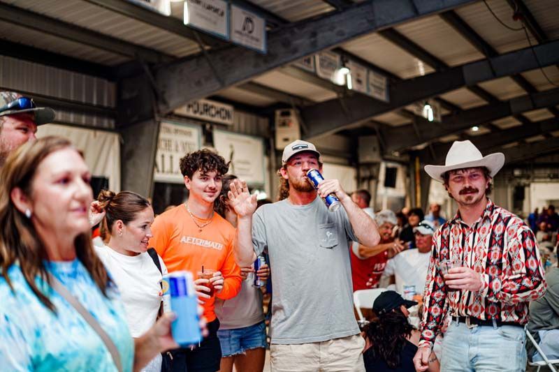 A group of people are standing in a room holding drinks.