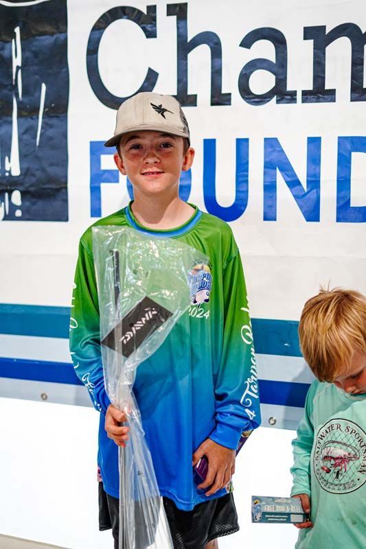 Two young boys are standing in front of a sign that says channel foundation.