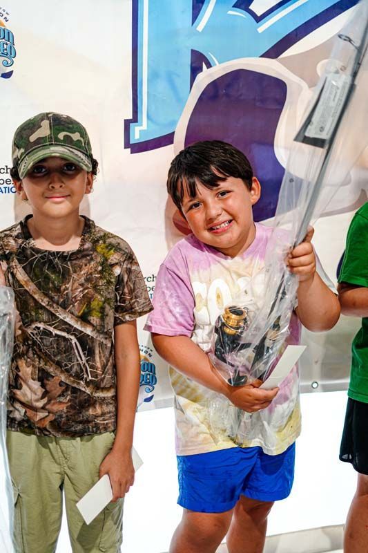Two young boys are standing next to each other holding awards.