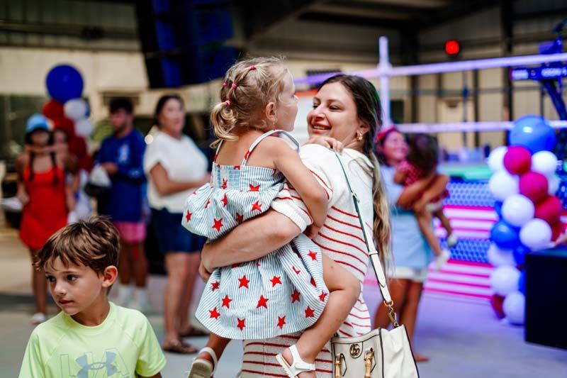 A woman is holding a little girl in her arms at a party.