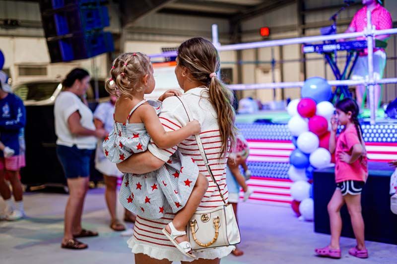 A woman is holding a little girl in her arms at a party.