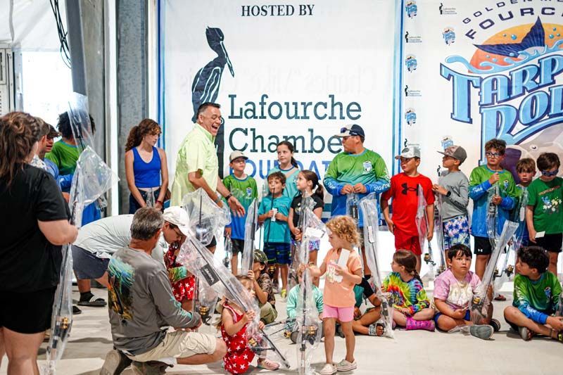 A group of people are gathered in front of a sign that says lafourche chamber of commerce.