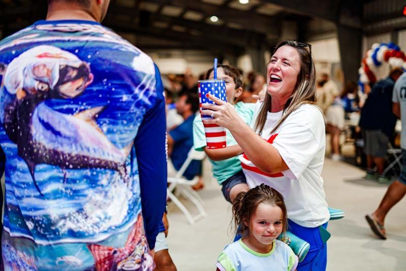 A woman is holding a child and a man is wearing a shirt with a dolphin on it.