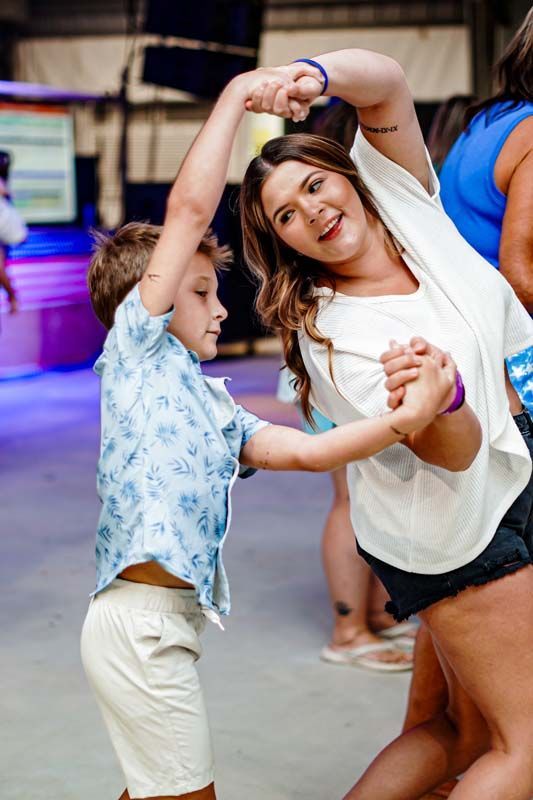 A woman and a boy are dancing together at a party.