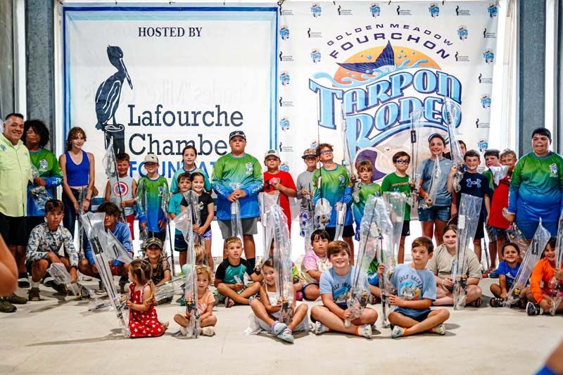 A group of children are sitting on the floor in front of a large banner.