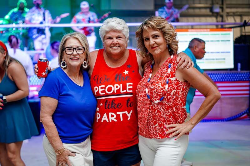 Three women are posing for a picture together at a party.