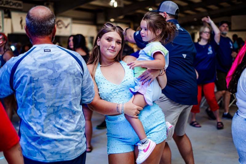 A woman is holding a little girl in her arms while dancing at a party.