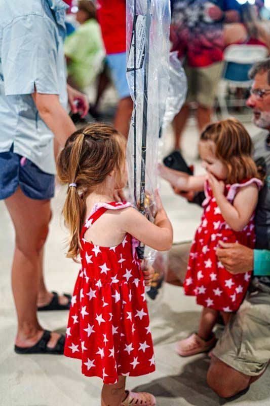 A little girl in a red and white dress is holding a balloon.