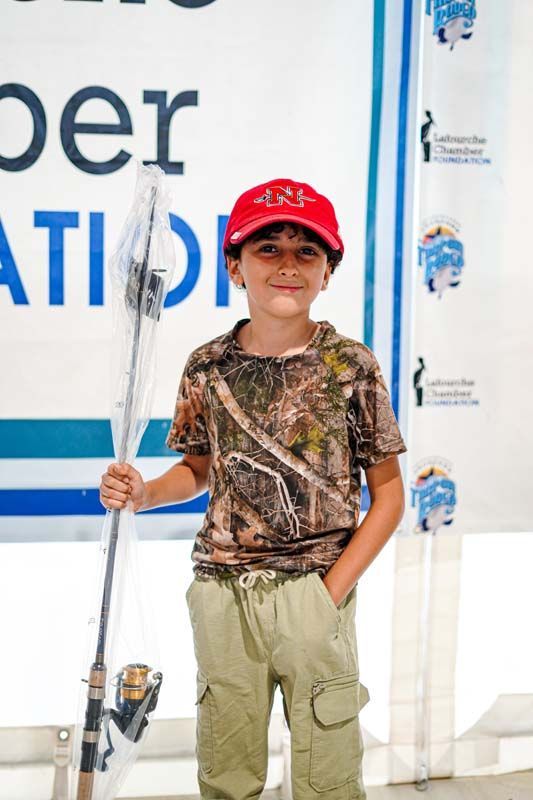 A young boy holding a fishing rod in front of a sign that says peration