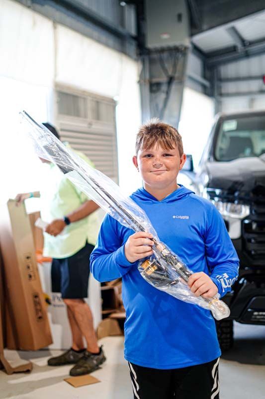 A young boy is holding a fishing rod in a garage.