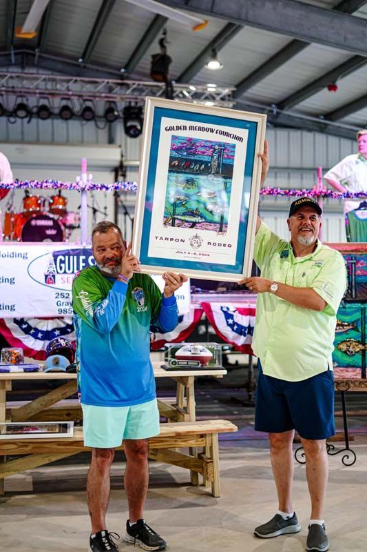 Two men are holding a framed picture in a room.