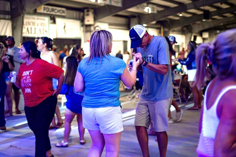 A group of people are dancing in a room with purple lights.