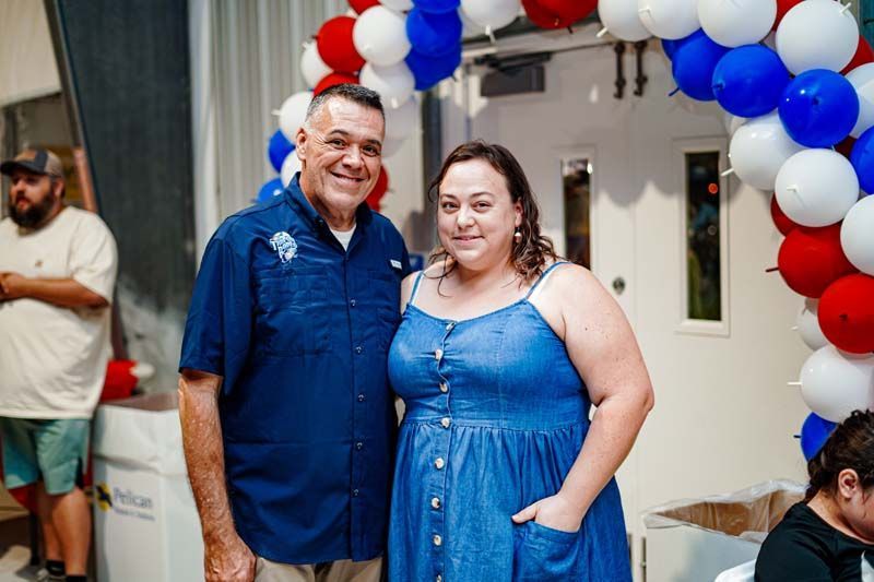 A man and a woman are posing for a picture in front of balloons.