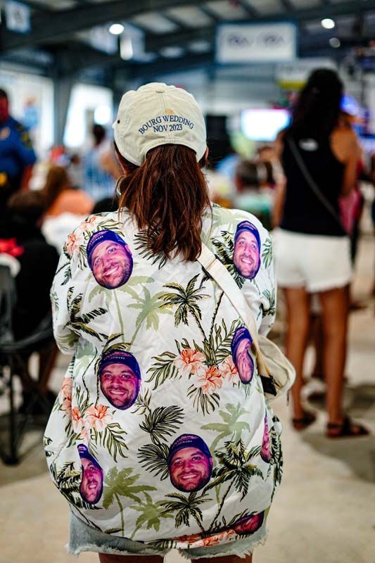 A woman wearing a hat and a shirt with faces on it.