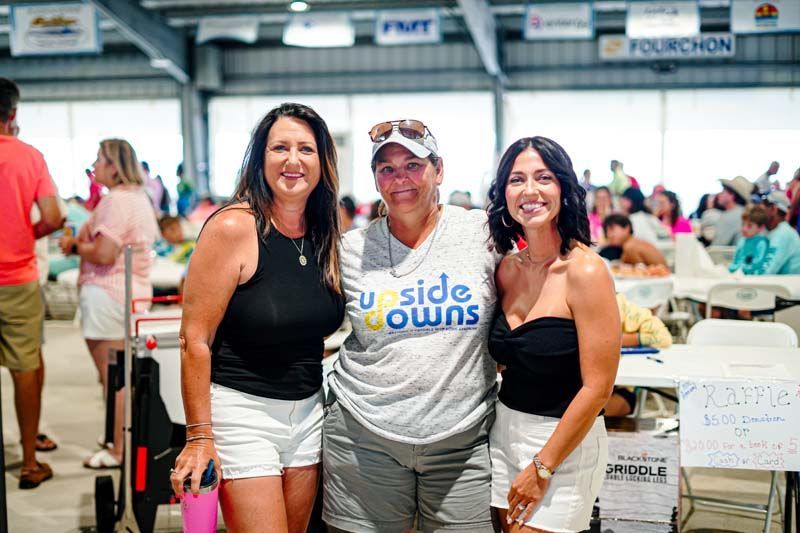 Three women are posing for a picture together at a convention.