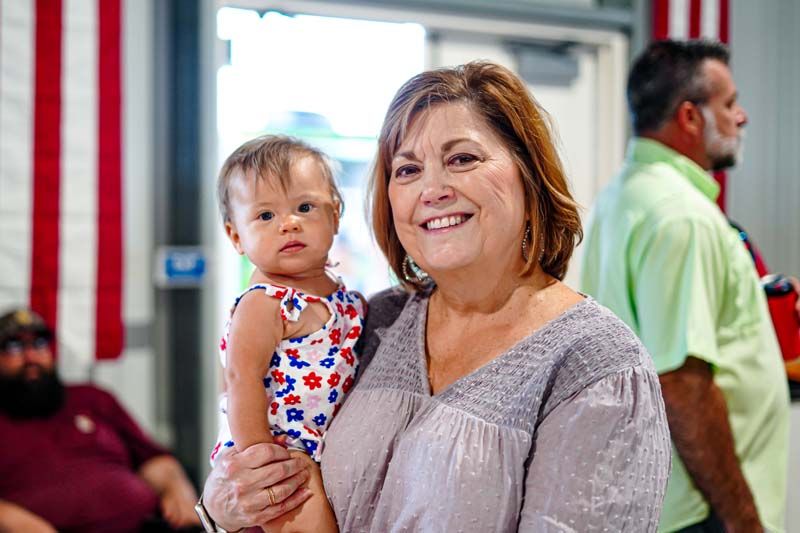 A woman is holding a baby in her arms and smiling.