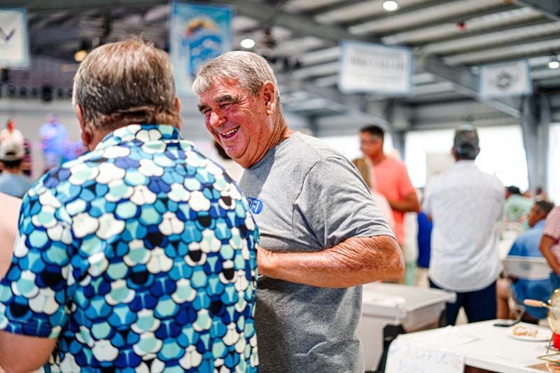 Two men are standing next to each other in a room talking to each other.